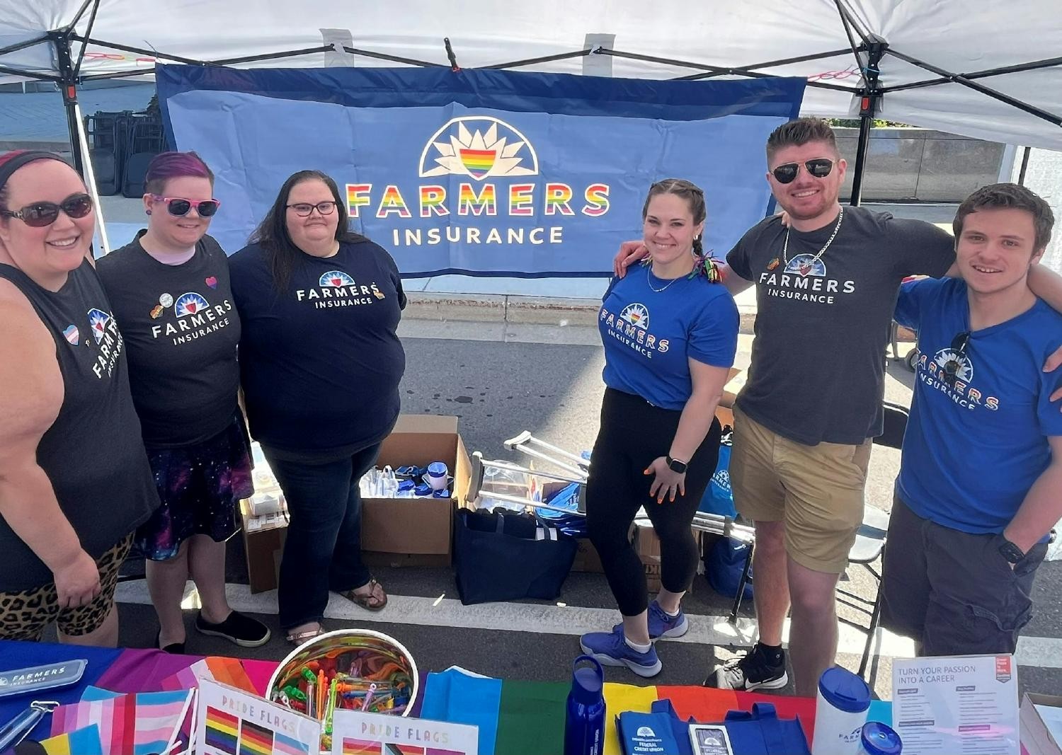 Members of the Farmers® Pride Employee Resource Group host a booth at a local Pride Parade Event.