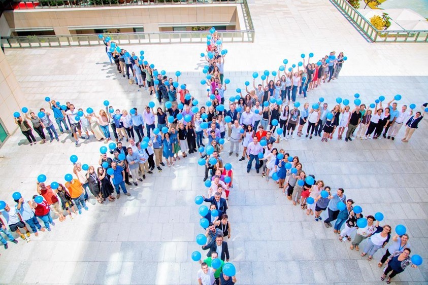 Employees gather to represent the Agilent “Spark of Insight” logo during a company celebration. 