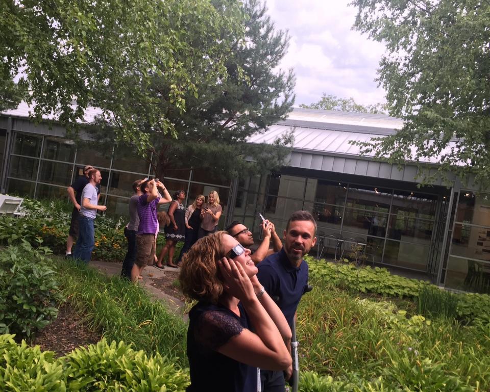 Staff members observe the solar eclipse from the courtyard