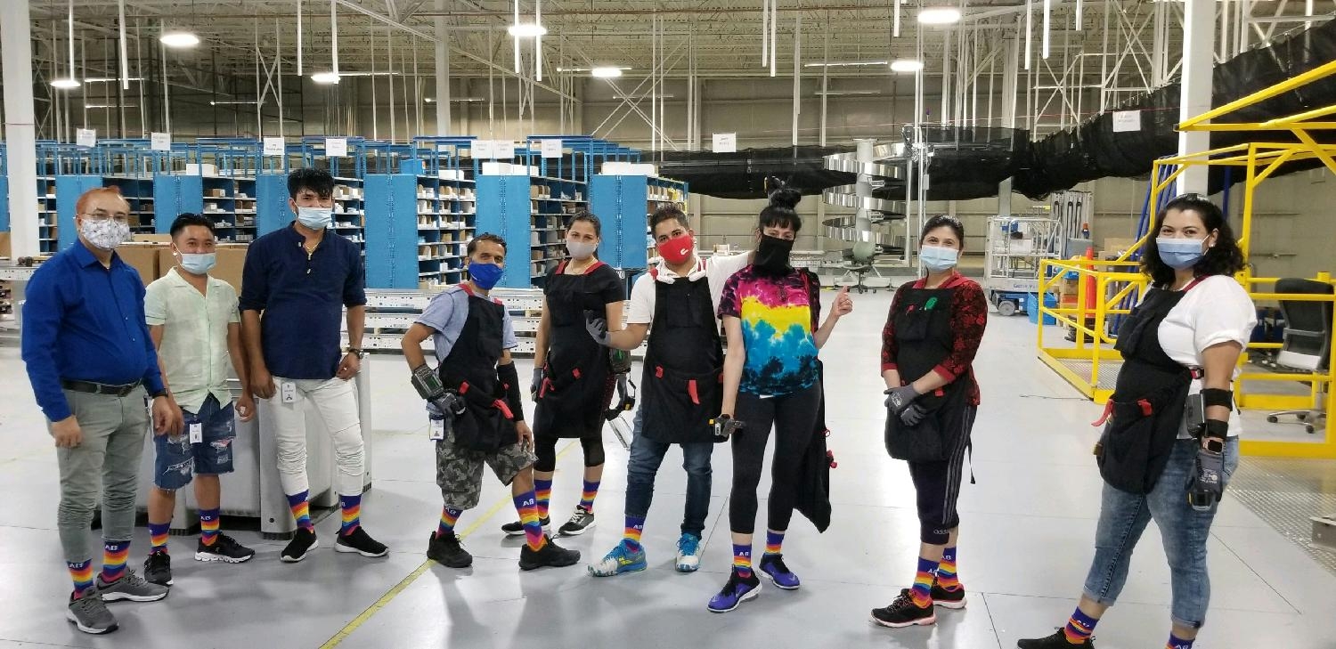 Distribution center team members show off AB's new brand with colorful AB socks representing we are 