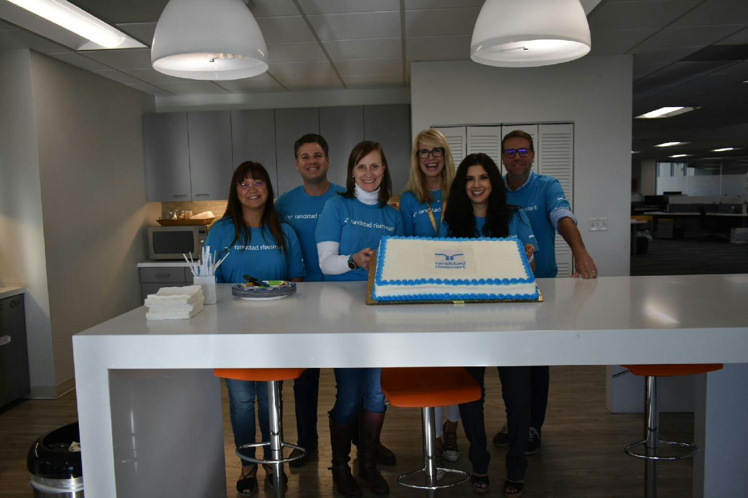 Additional team members celebrate the Randstad RiseSmart office rebrand with a cake. 