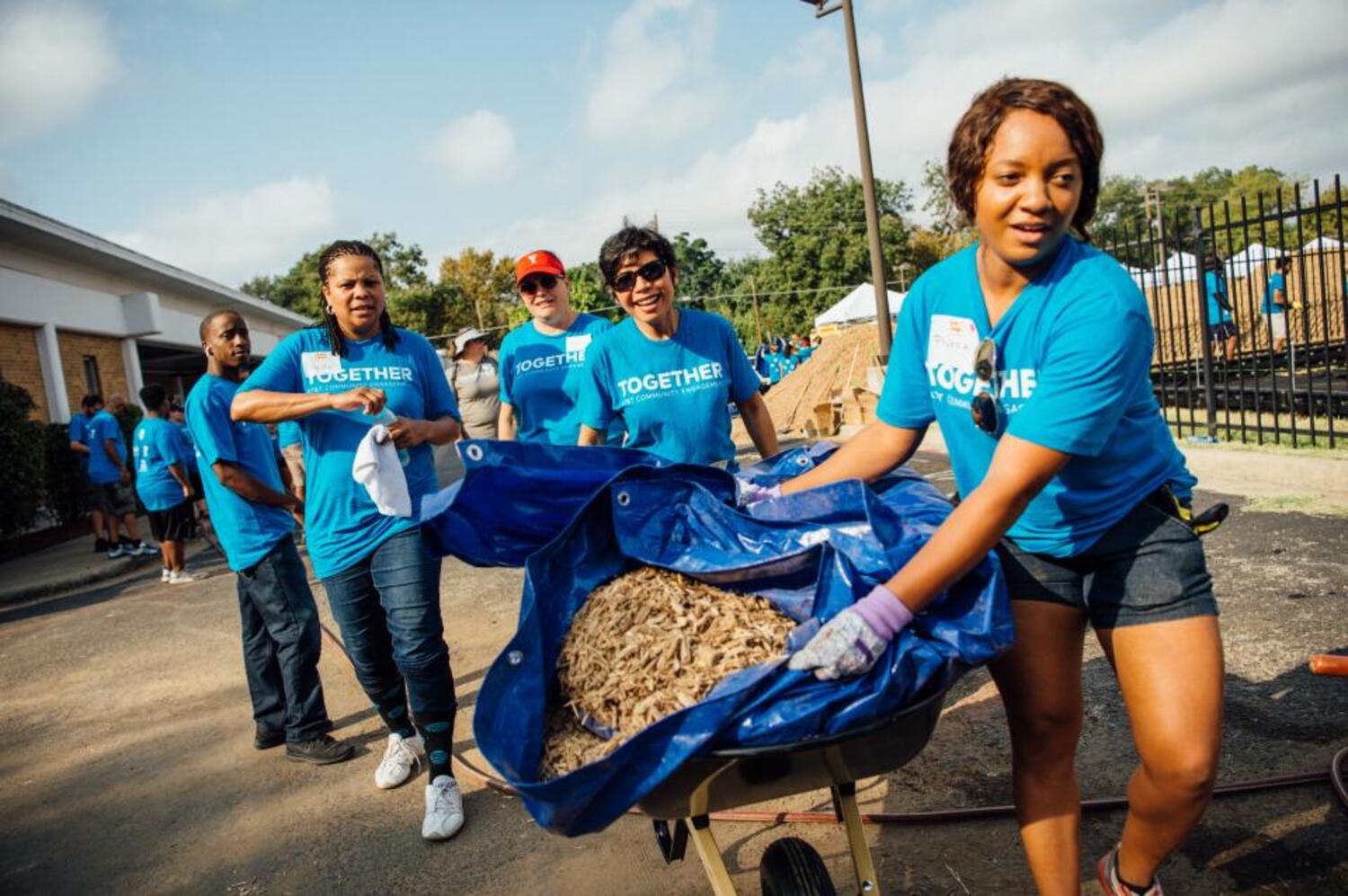  Employee resoThis is one of many employee resource groups in the nation. This group of cowokers are wearing blue t-shirts and hauling woodchips at a Contruction site.urce groups are depicted with coworker