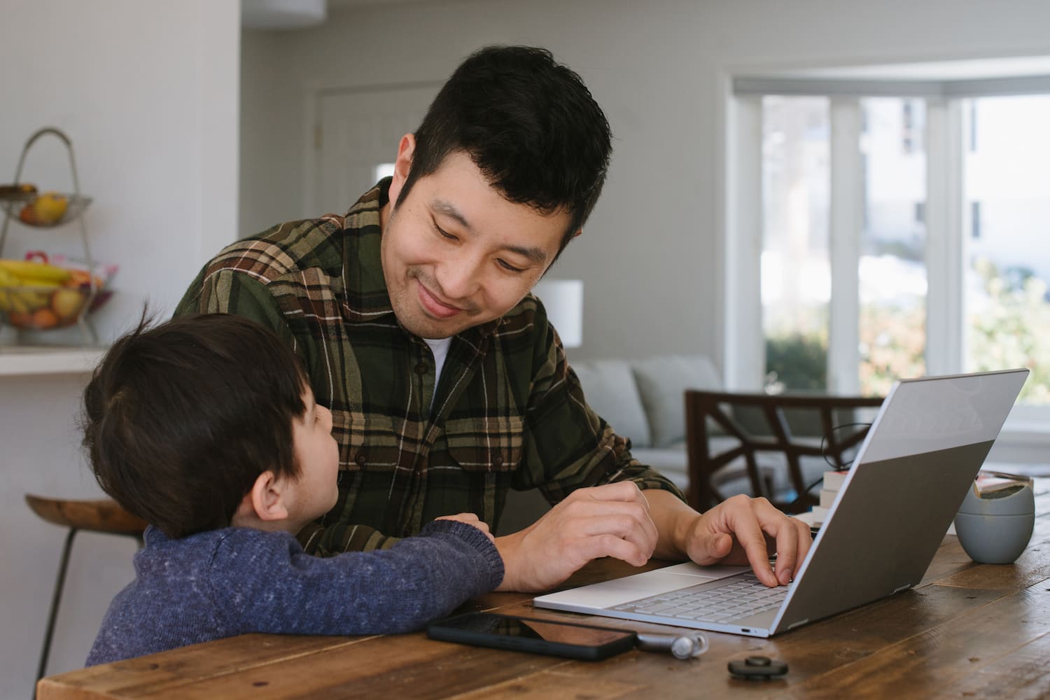  Dad working on his laptop, pauses to speak to his young son