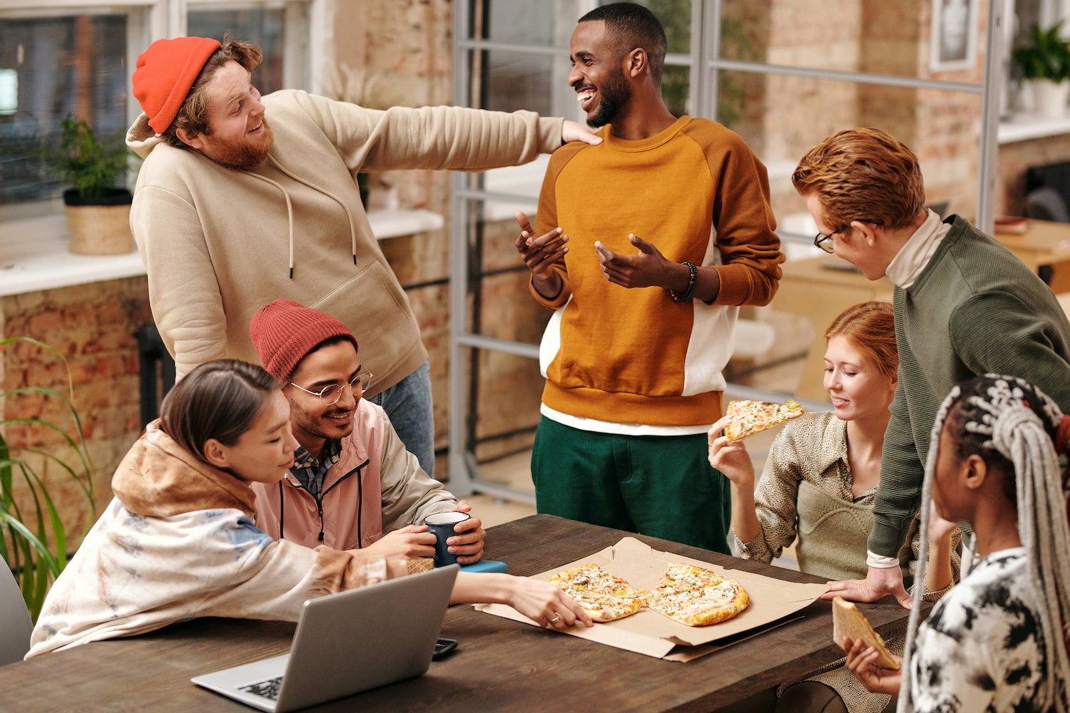  Gen Z employees enjoy pizza during a work meeting.