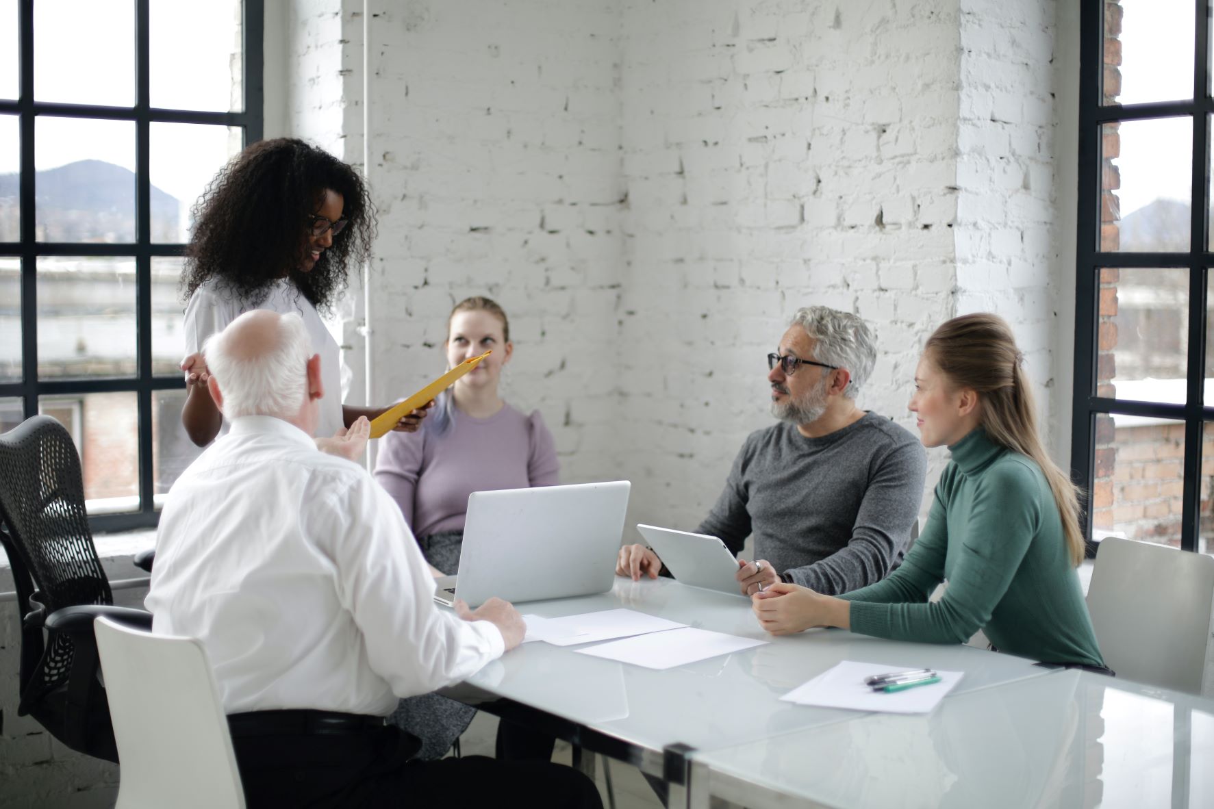  Managing a multigenerational workforce is depicted with a coworkers in a meeting room. They are a diverse group of people including young and older employees.  