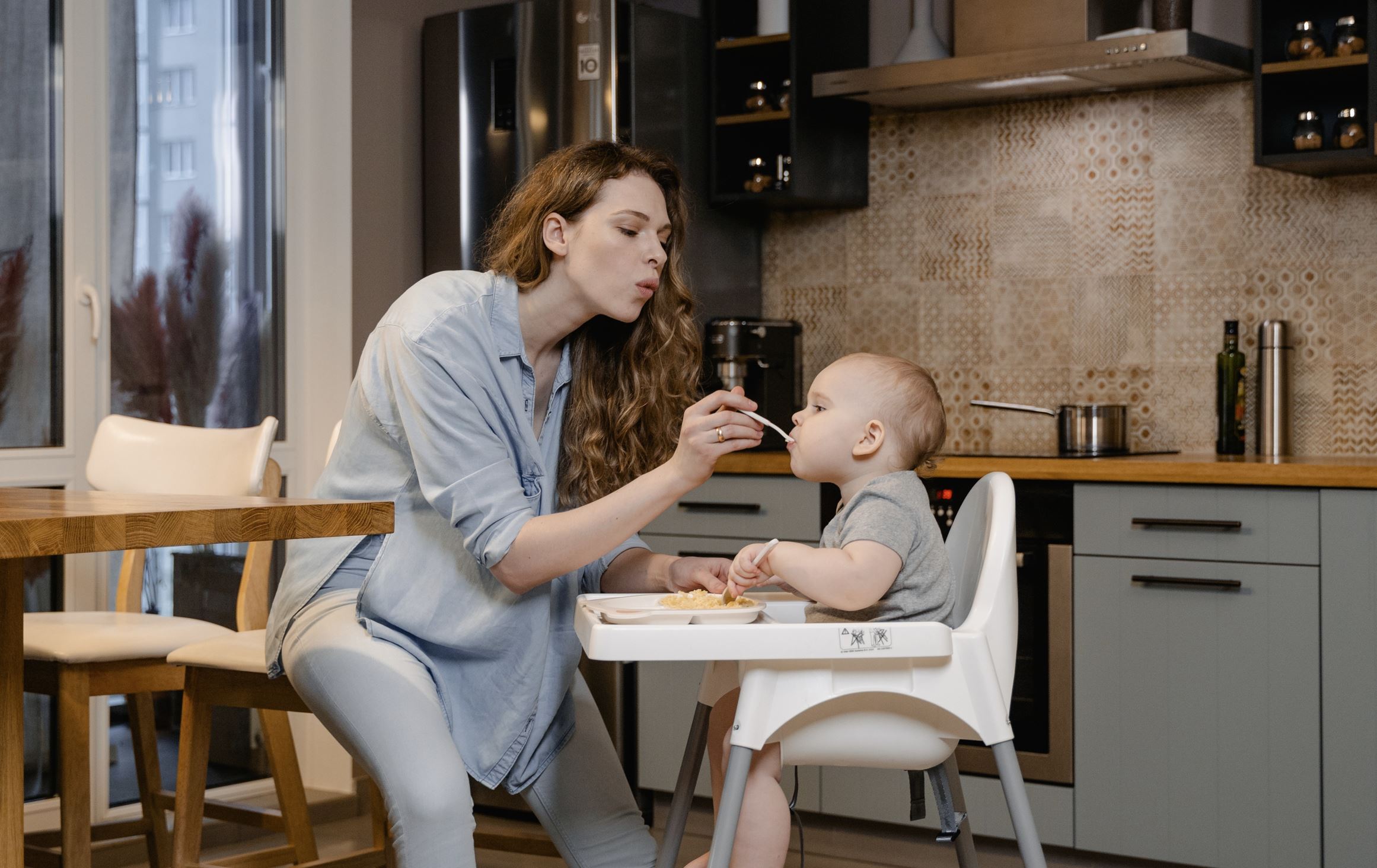  Paid parental leave policy is depicted with a mom feeds her toddler at home while on her maternity leave