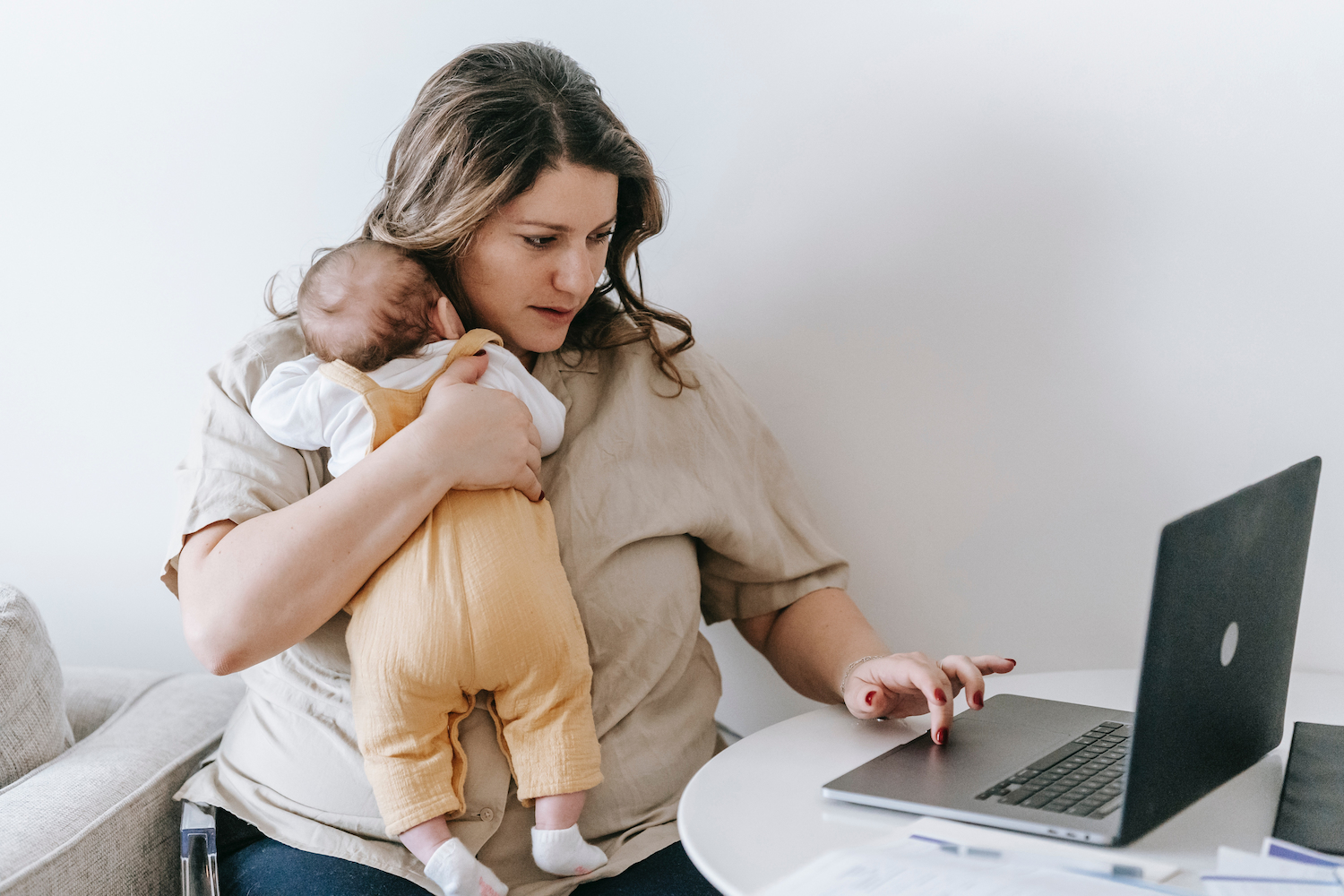 Workplace wellness trends is depicted with a working mom juggles baby care with work