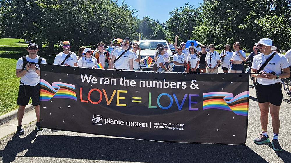 Smiling staff members support each other during a local Pride festival.