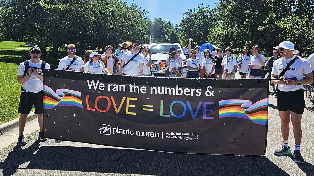 Smiling staff members support each other during a local Pride festival.