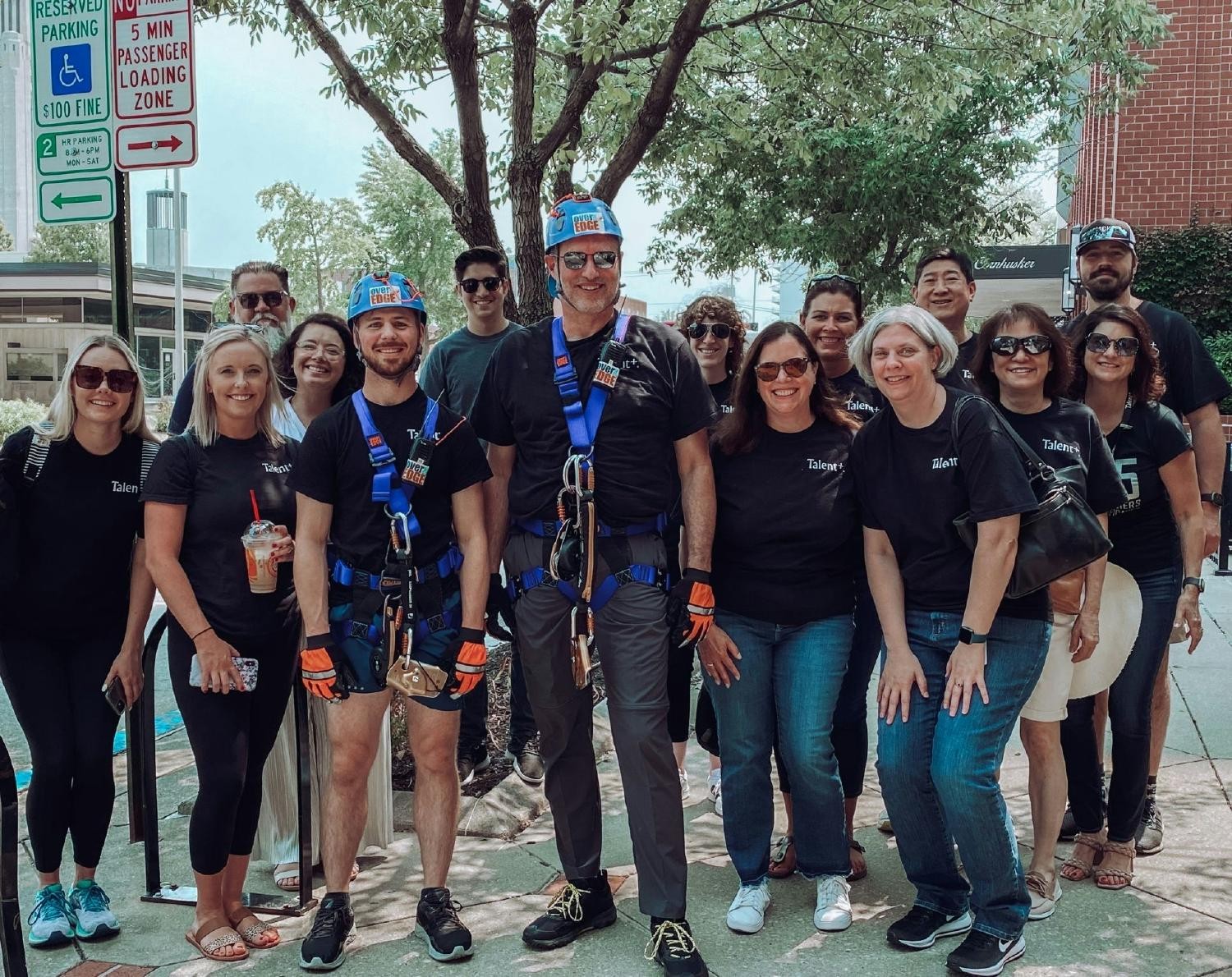 Steve Oss, CFO, over the edge of a downtown Lincoln building for Boy Scouts with Talent Plus colleagues cheering him on