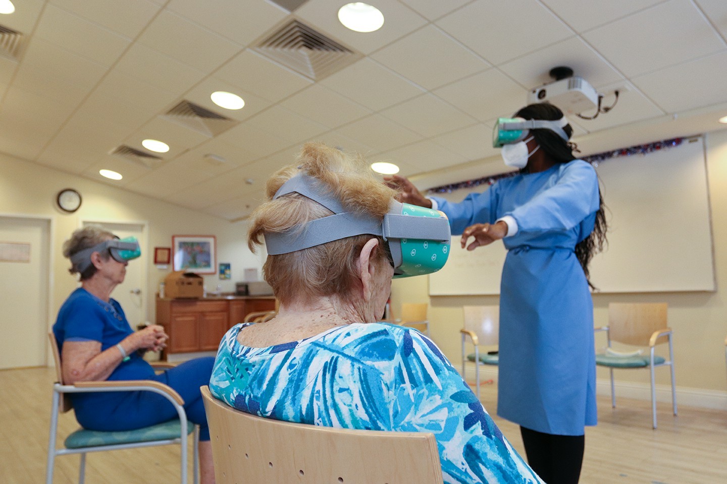 Activity assistant performing life-enhancing virtual reality therapy with memory care residents. 