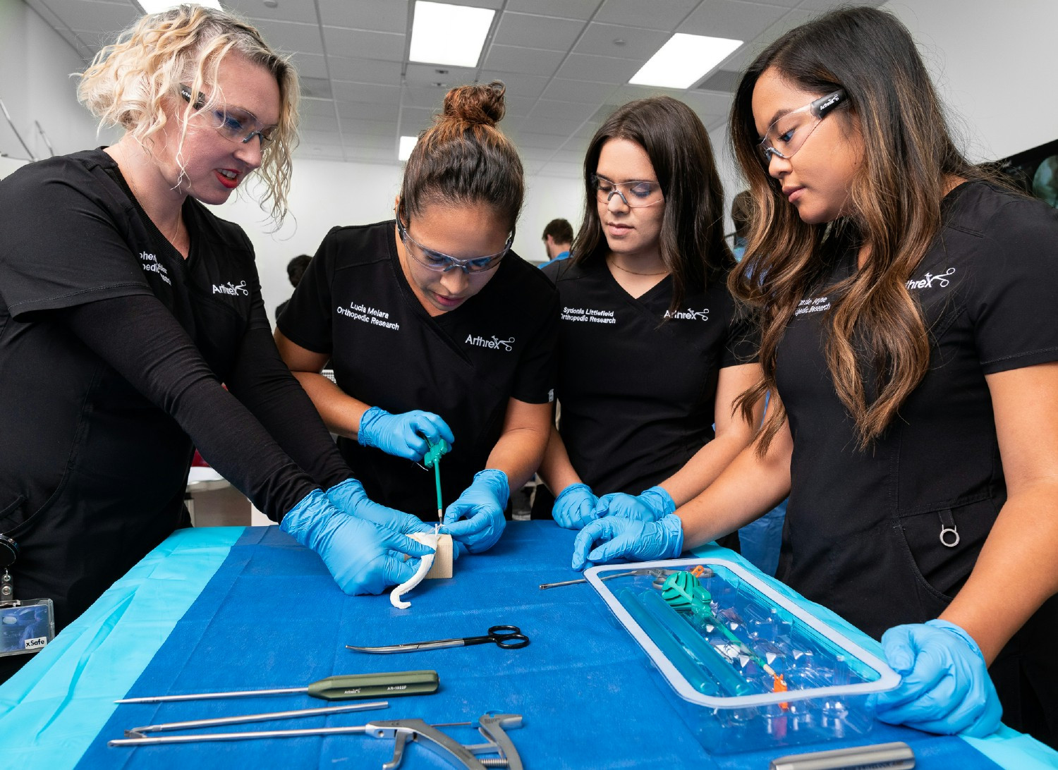 Arthrex Manufacturing Inc. Suture employees discuss placement of the suture on a card to prepare it for packaging.