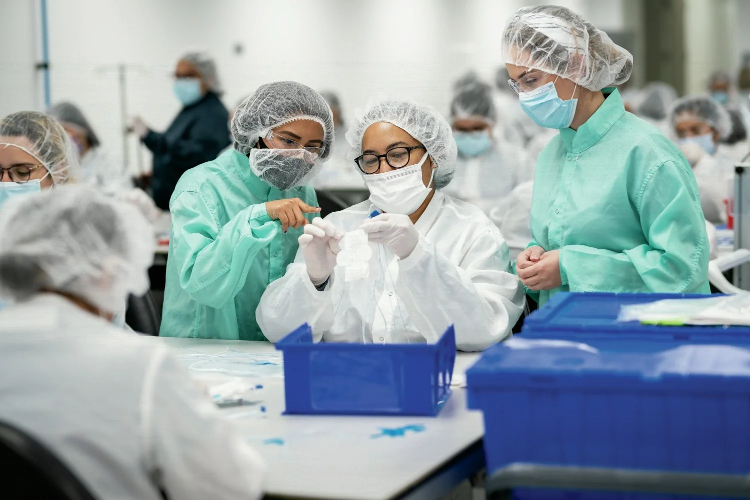 Arthrex Manufacturing Inc. Suture employees discuss placement of the suture on a card to prepare it for packaging.