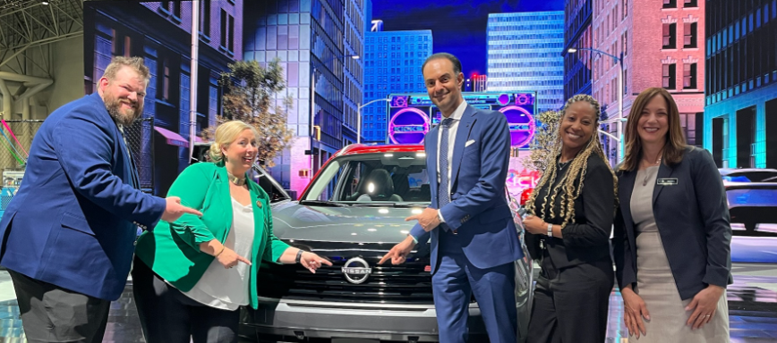Nissan professionals unveil new Nissan car model at an auto exhibition.