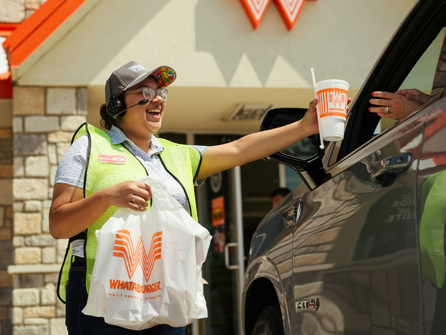 A Whataburger Family Member delivers curbside with a smile, bringing hospitality to every guest.