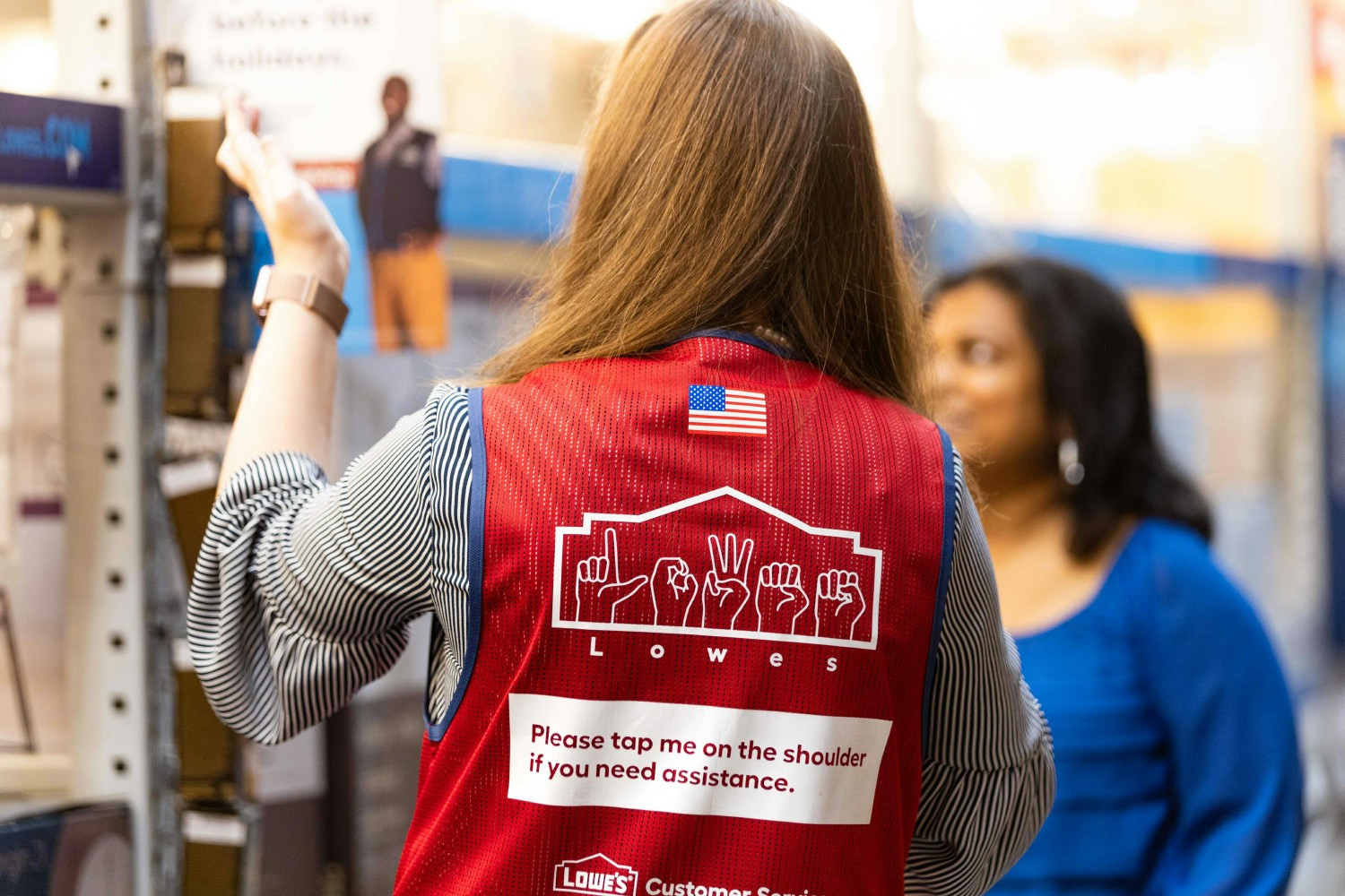 Associate who is deaf wearing an American Sign Language (ASL) vest in a Lowe’s store helping a customer.