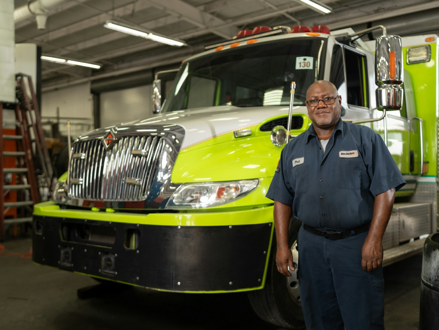 Empleado posando frente a un vehículo, mostrando su compromiso y experiencia en el mantenimiento de equipos.