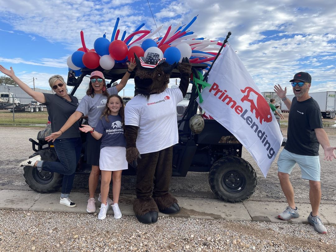 Team members enjoy sponsoring community events like this 4th of July parade with Mo, our PrimeLending mascot!