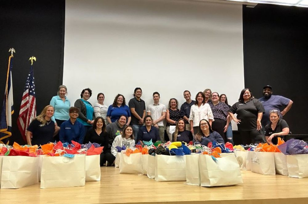 Employees come together on stage after volunteering to support the local community - giving back with heart and purpose.