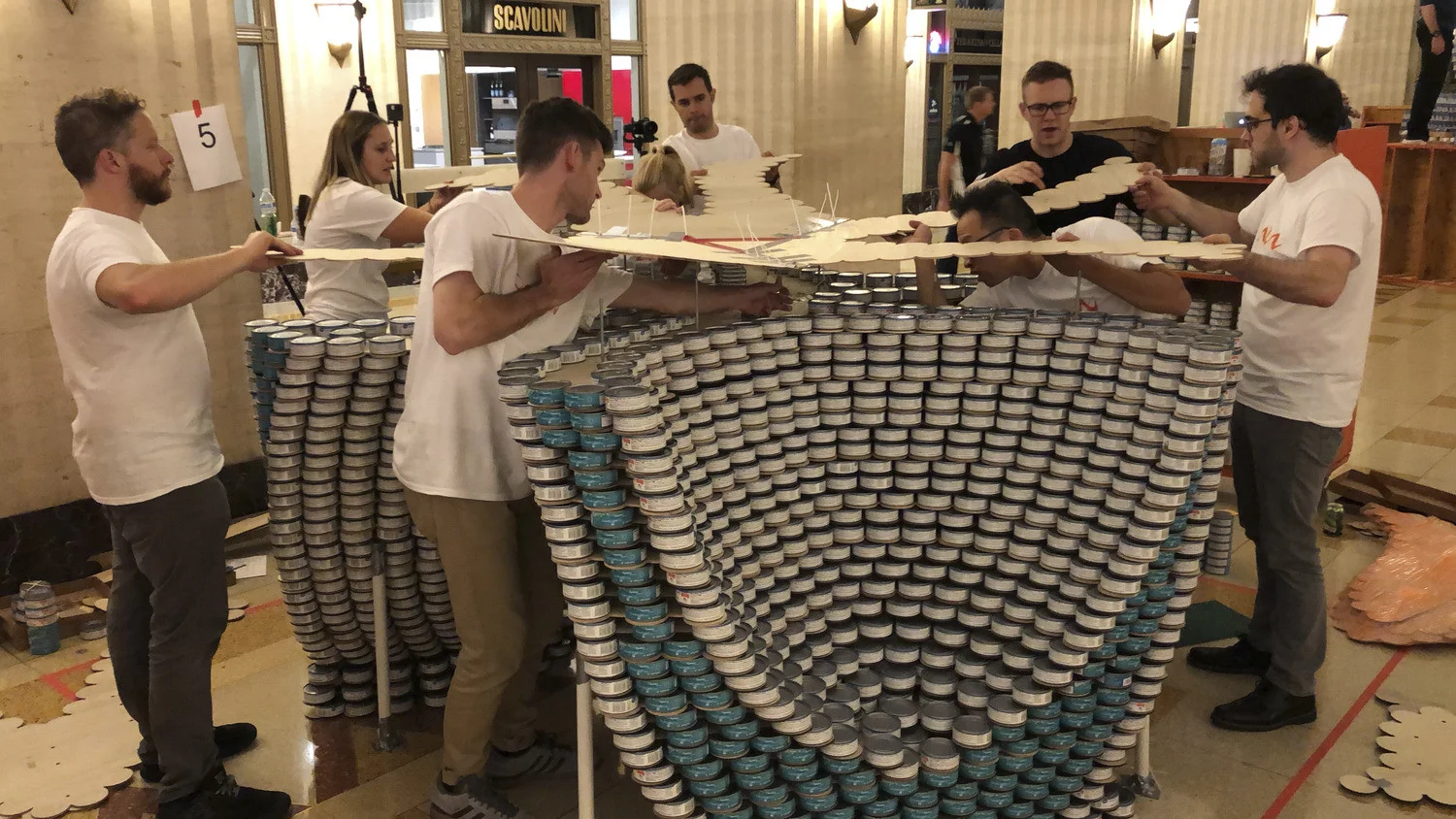 Woolpert teammates participate in an exhibition of structures made from unopened cans of food that are later donated.