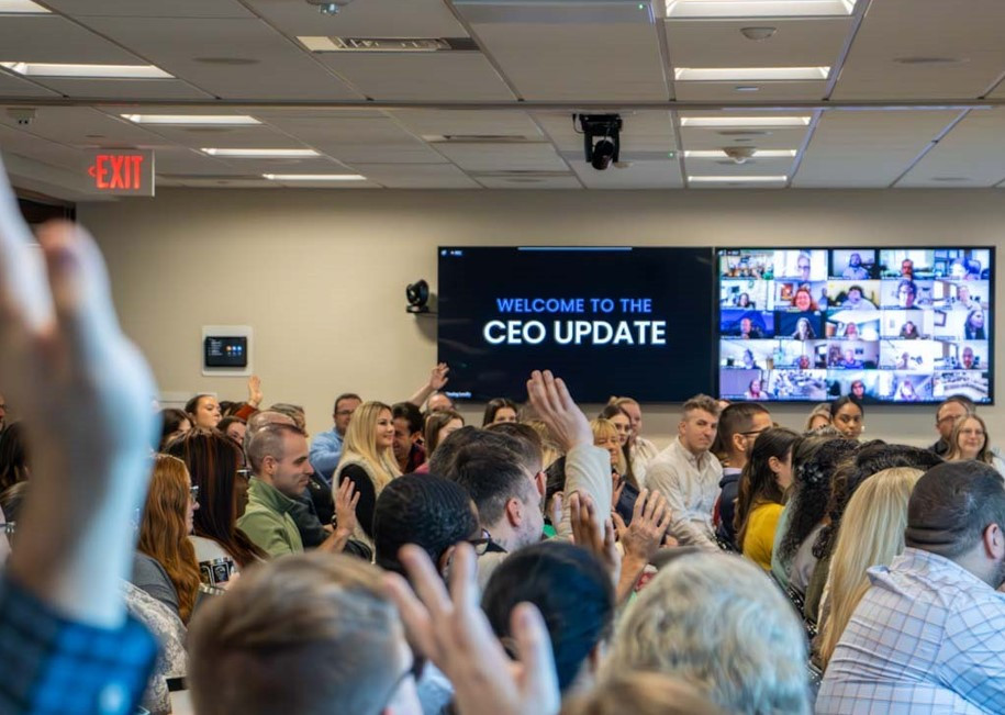 Onsite staff give a show of hands during our fall CEO Update, while hundreds more join via Zoom conferencing.