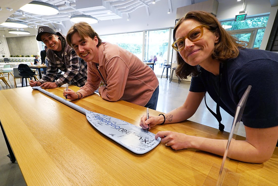 Employees sign an oar to celebrate paddling together and achieving a major company milestone. 