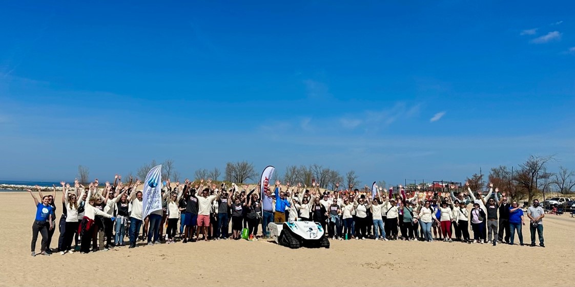 Team members volunteer to clean up area beaches. Pictured with the Meijer-sponsored beach-cleaning robot, the BeBot.