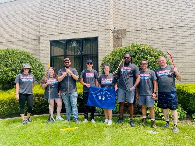 Team members volunteer to clean up area beaches. Pictured with the Meijer-sponsored beach-cleaning robot, the BeBot.