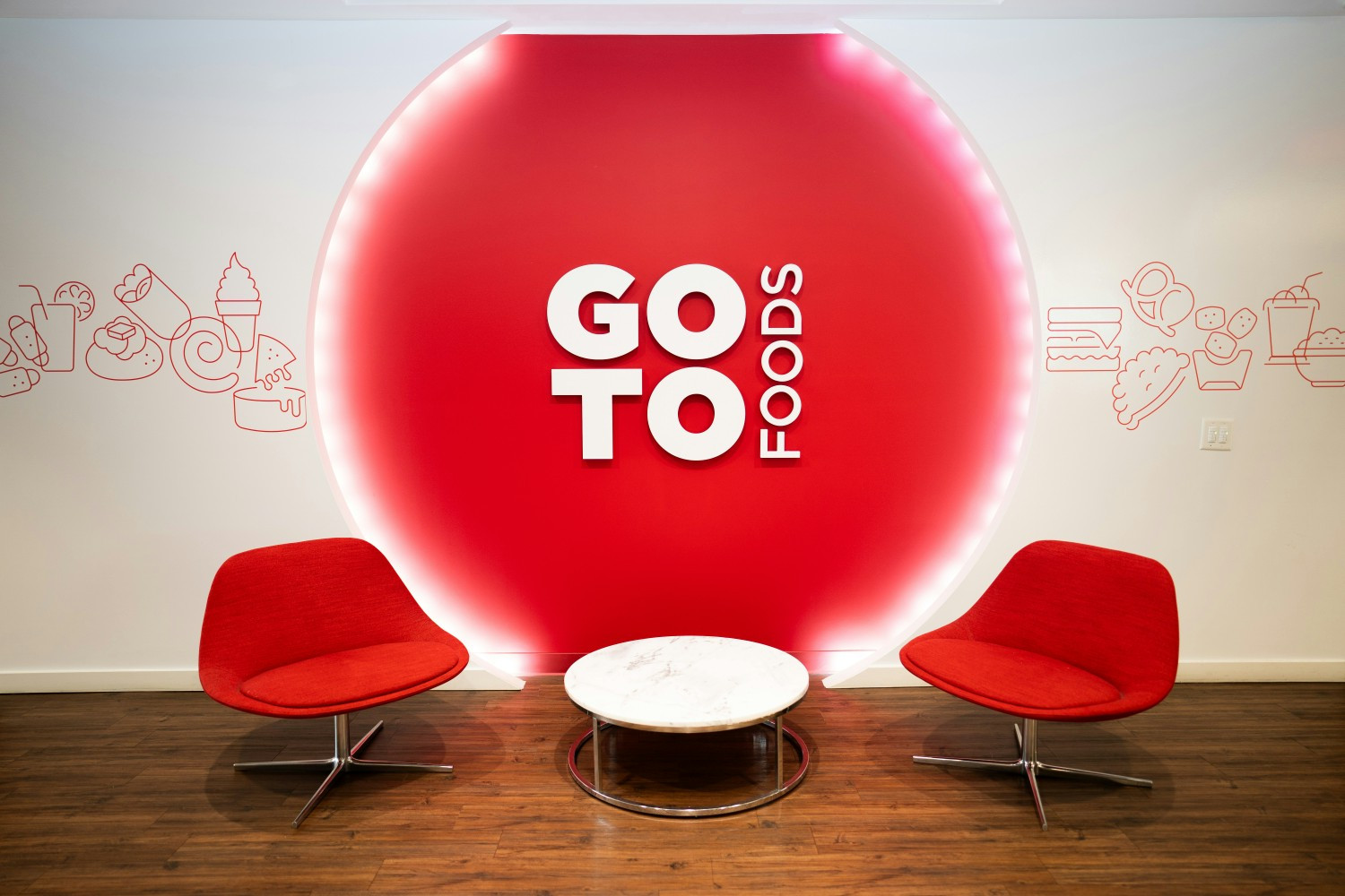 A third-floor seating area in front of a decorative GoTo Foods wall panel at the GoTo Foods headquarters. 