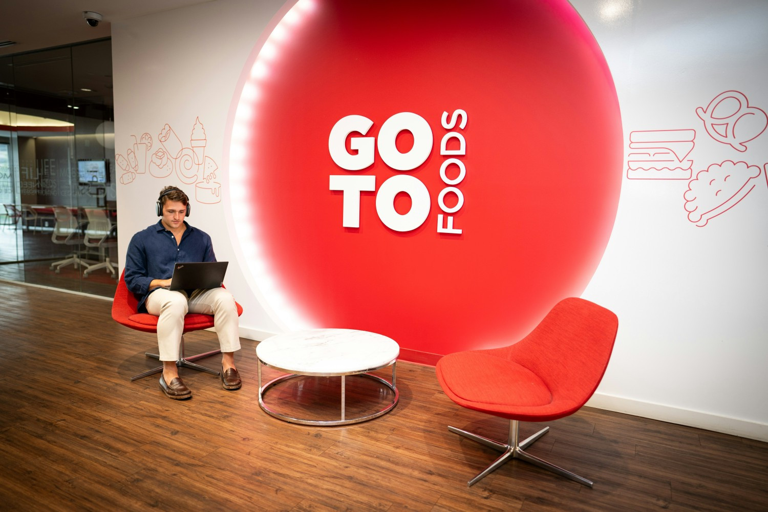 A GTF employee is diligently working on his laptop in front of the decorative wall panel in the GoTo Foods office. 