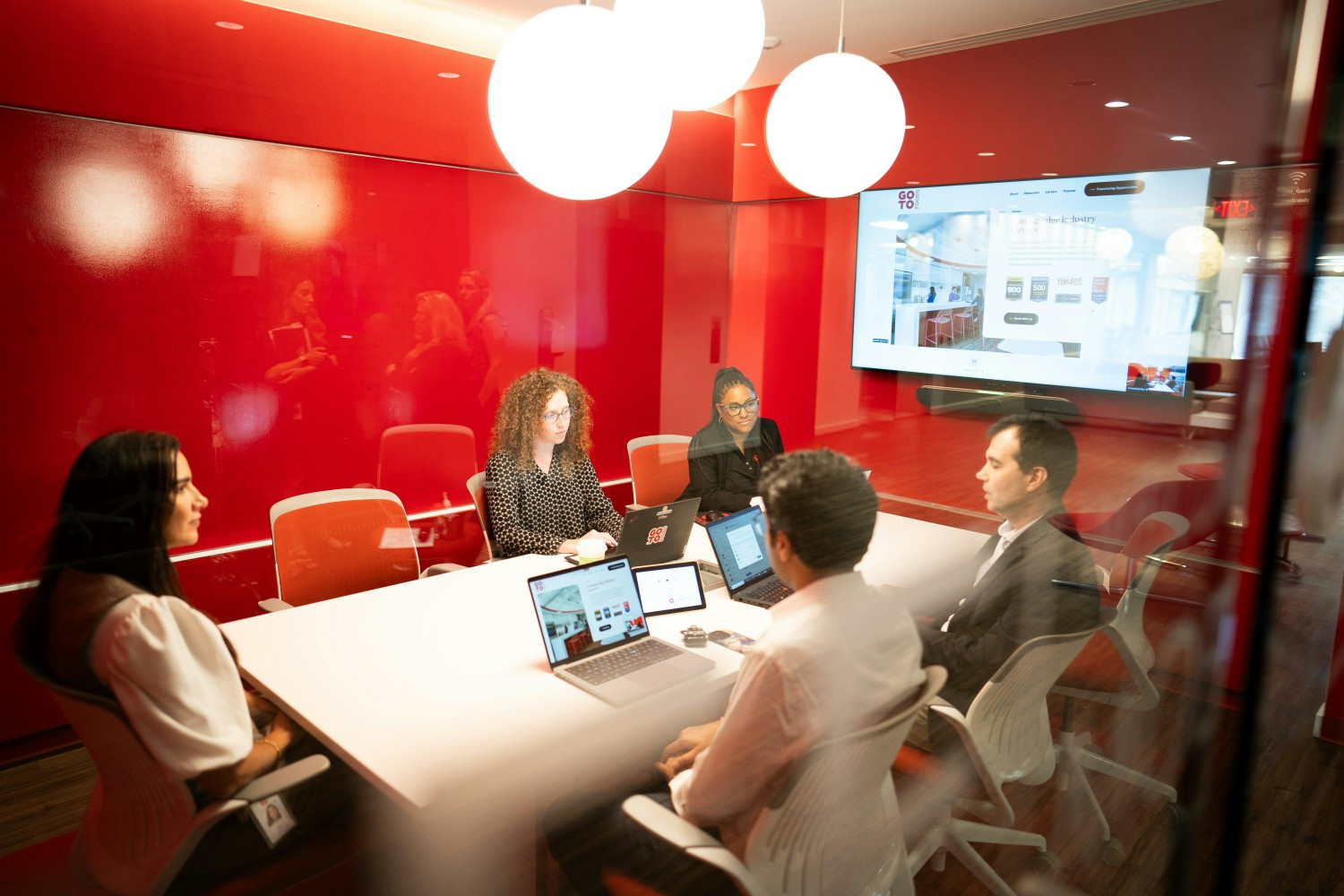 A group of GoTo Foods employees are convening in one of the conference rooms at the GoTo Foods headquarters. 