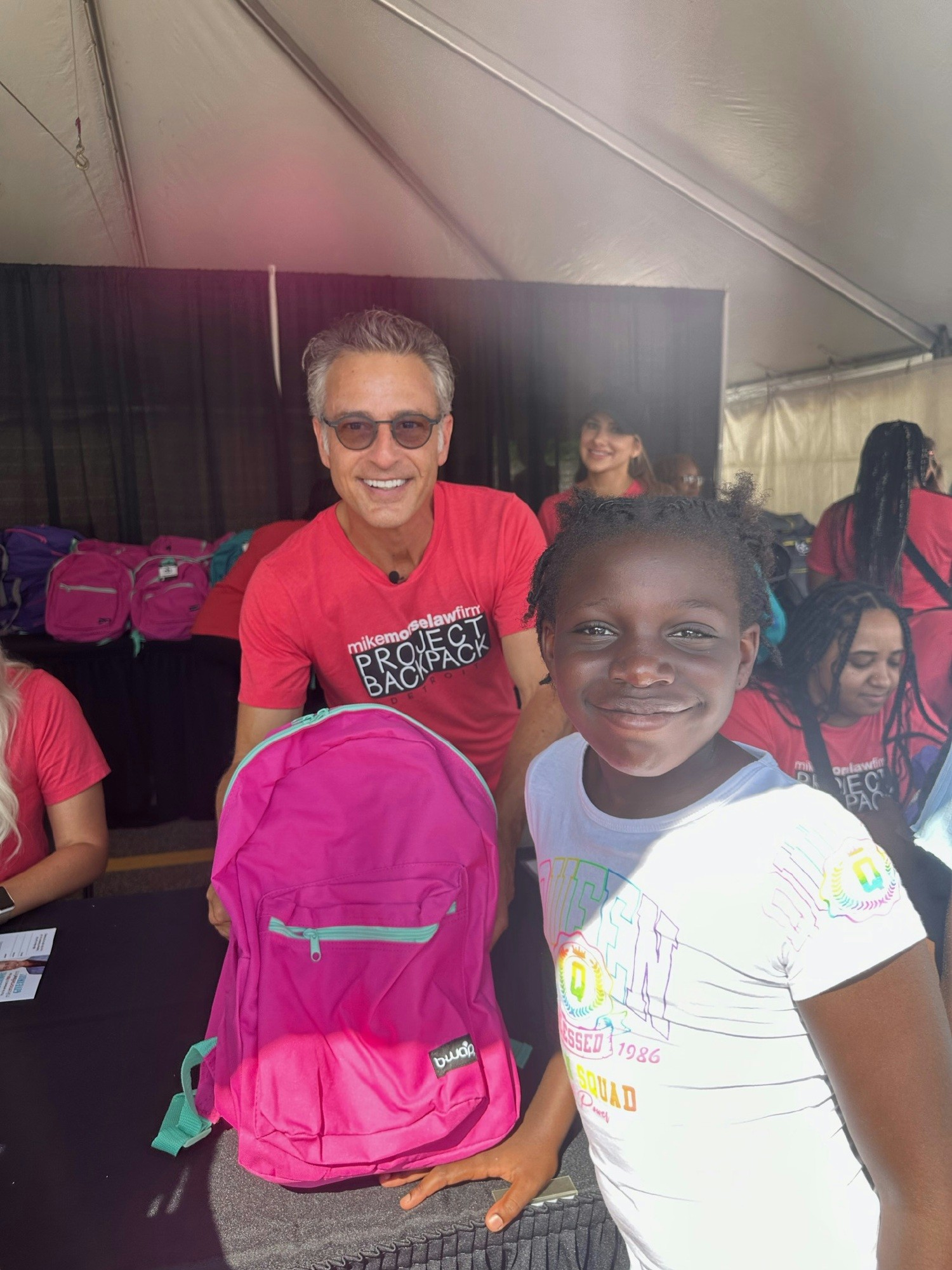 A happy metro-Detroit student receives her backpack filled with school supplies from Mike Morse.