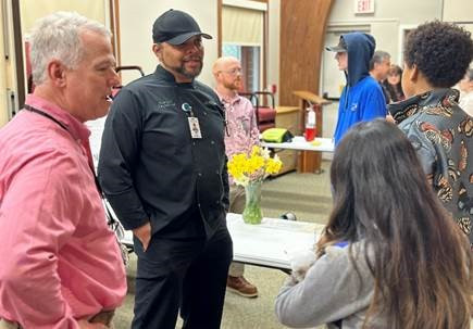 Staff members answering questions from a group of visiting high school students.