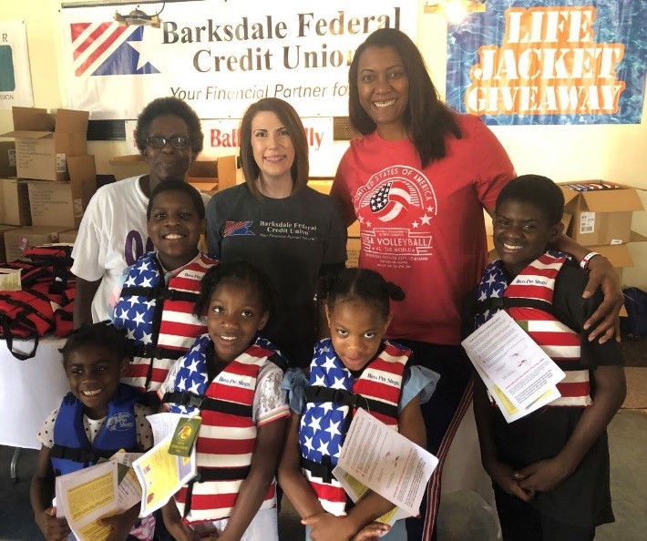 Employees participating in the annual life jacket give a way where children are outfitted with free life jackets.