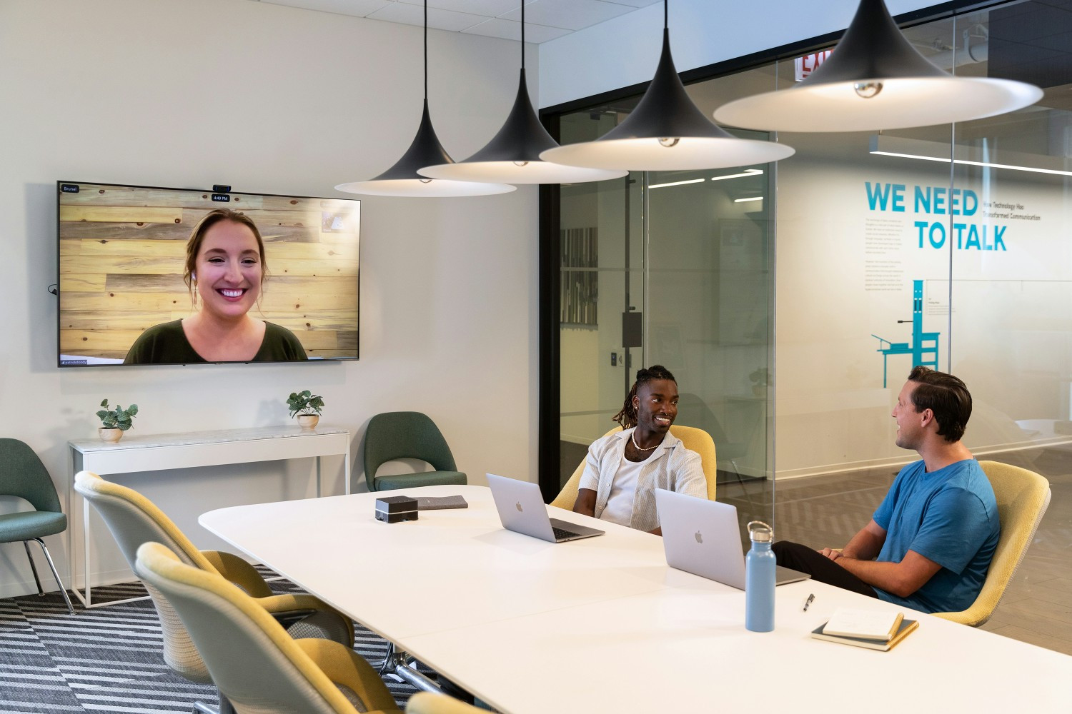 A group of employees having a meeting both in the office and remotely.