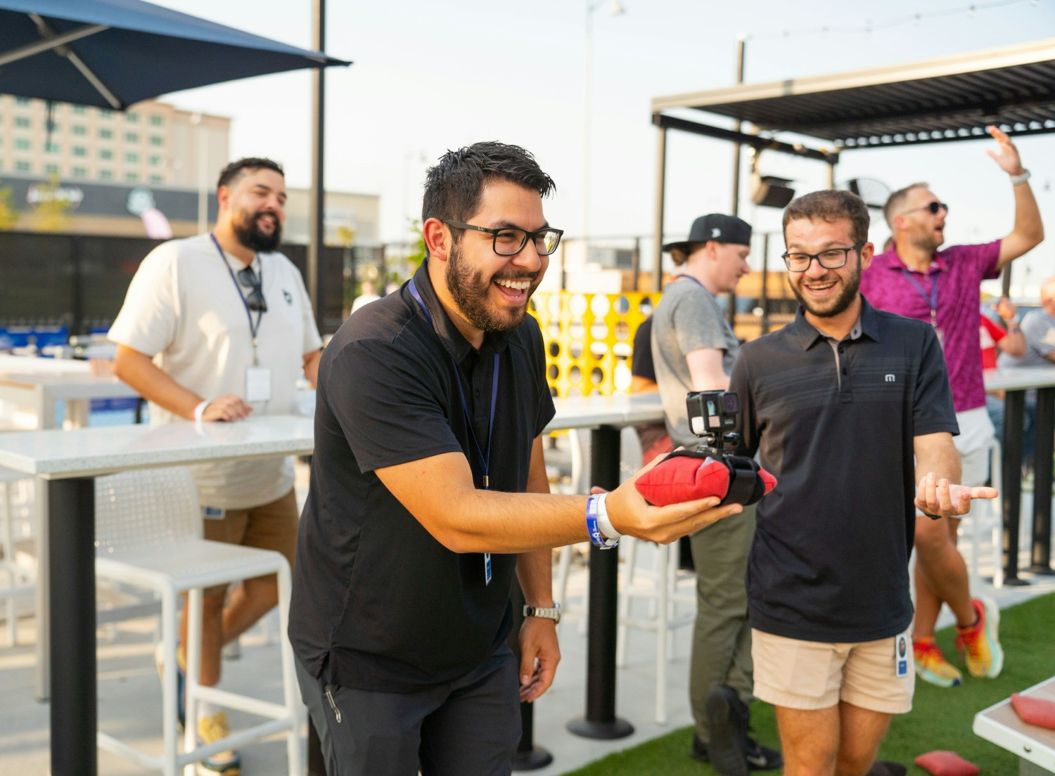 Zach, a Sales Executive, enjoying a game of bean bag toss and socializing with coworkers at an outdoor company event.