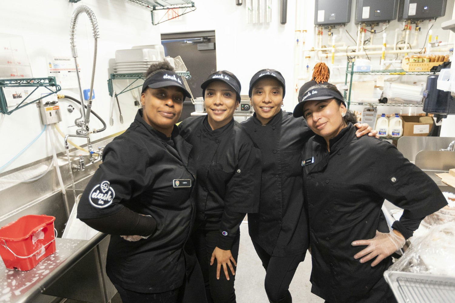 Dash In employees showcasing teamwork and dedication as they prepare high-quality food for customers with a smile.