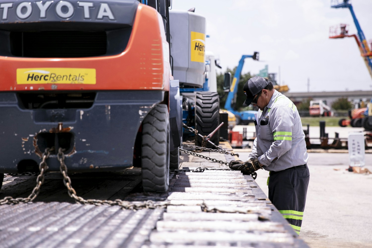 A tractor trailer driver secures equipment to the truck before making a delivery. 