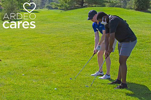 An Ardeo golfer helps an AIM High student learn the game at a benefit golf outing 