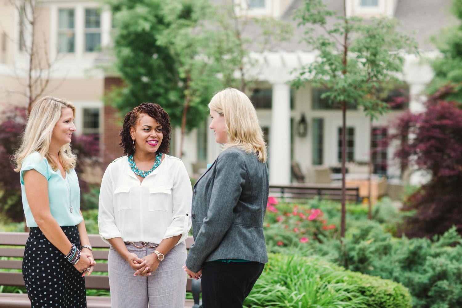 Three associates enjoy a chat outside their community.