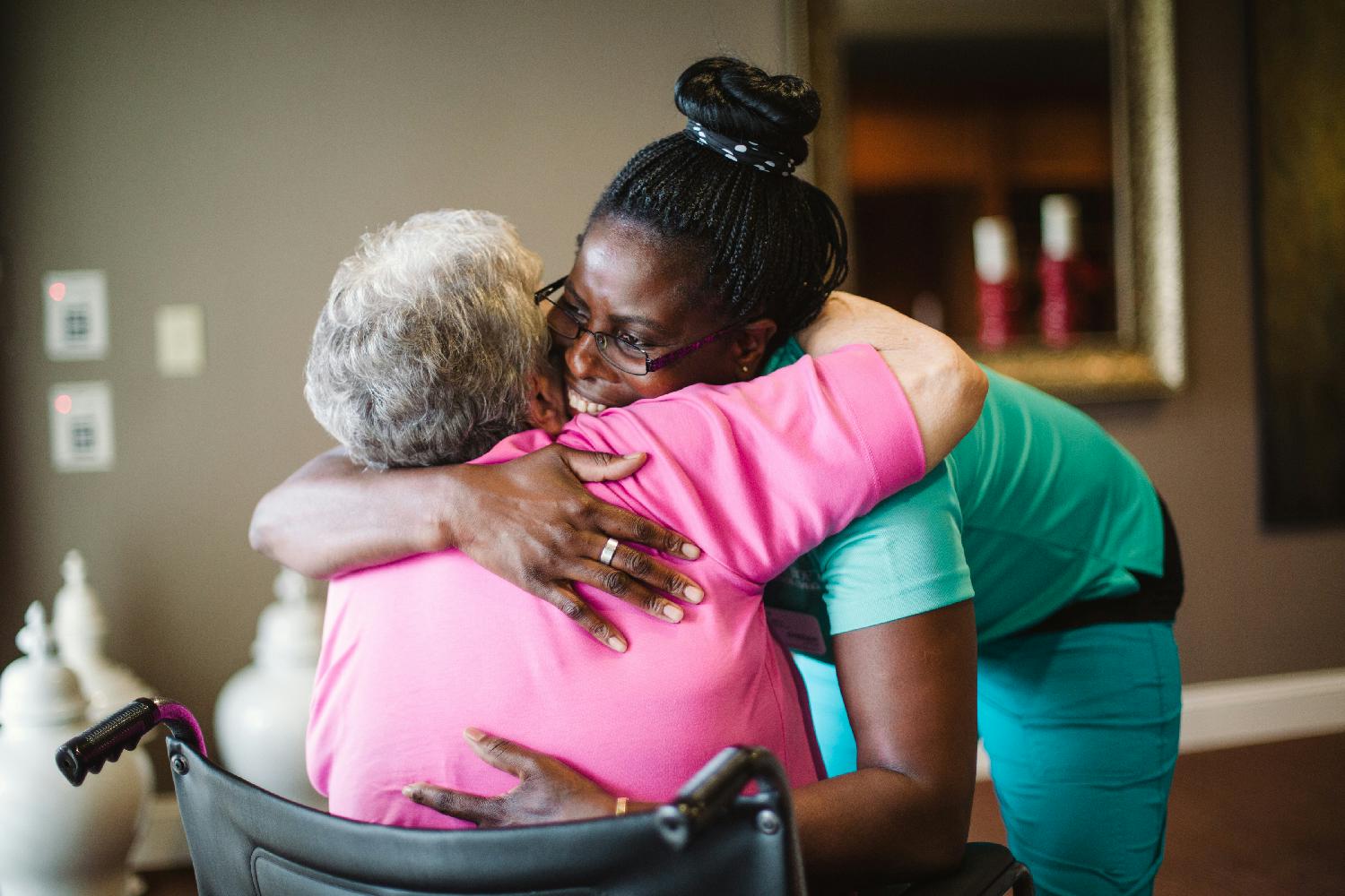 A caregiver warmly embraces a resident.