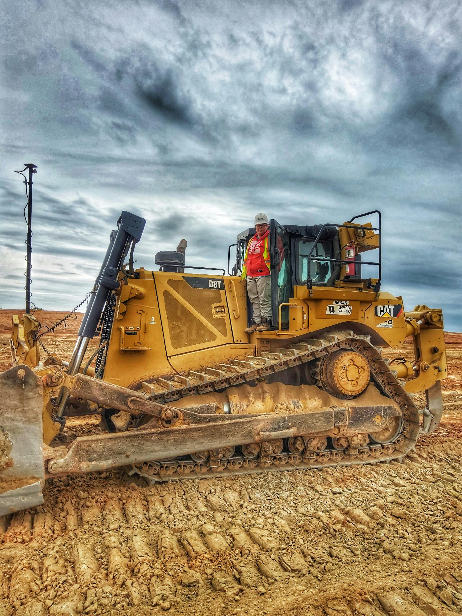 Dozer operator Jordan Ledford stands on her machine.