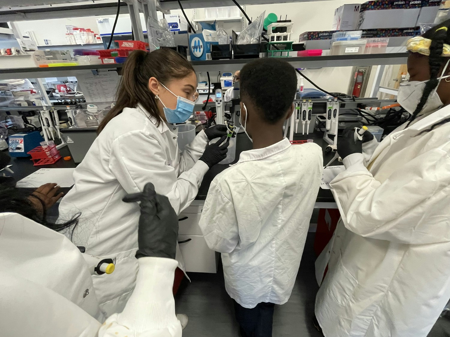 A member of the Molecular Biology team demonstrating pipetting skills to Project Onramp students.
