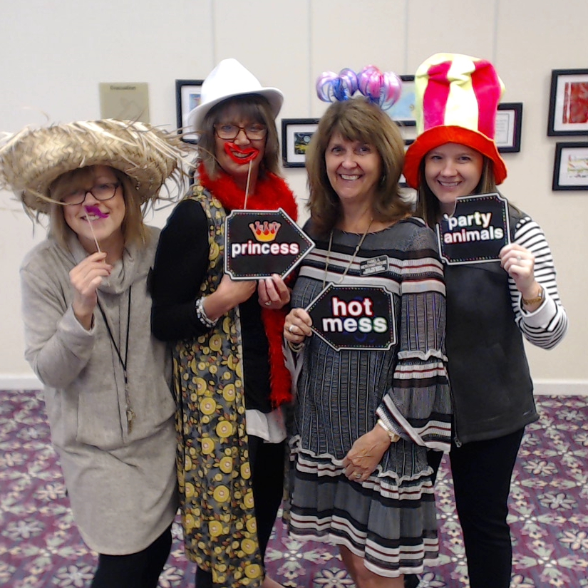 Employees celebrating a perfect State Department of Health survey with photo booth props.