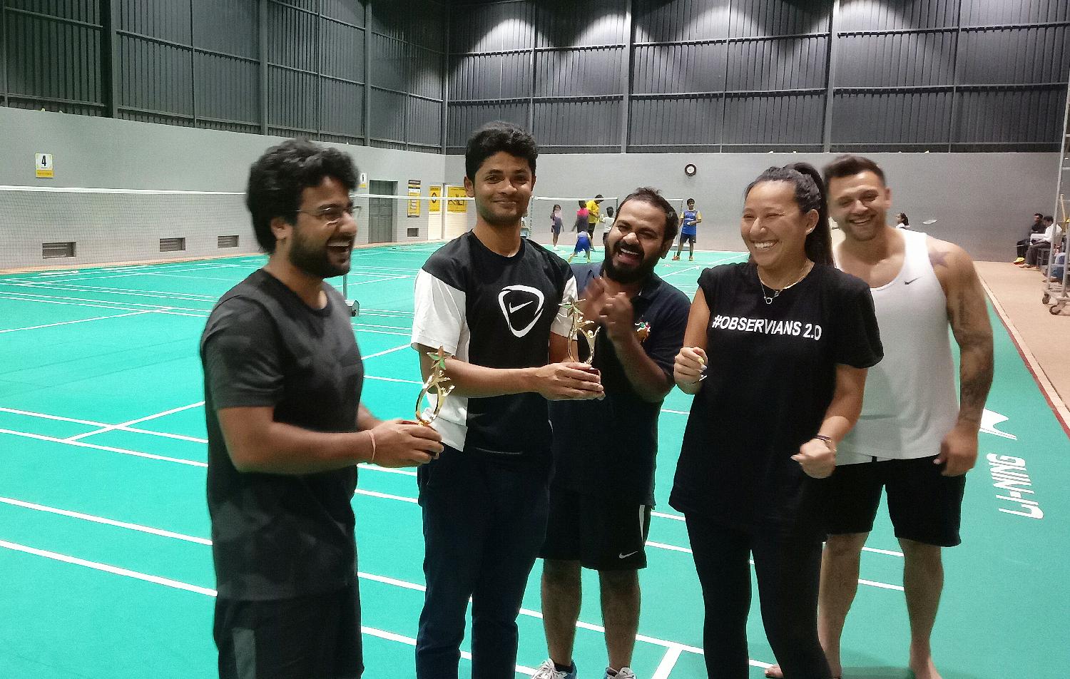 Observe team members laughing after a competitive game of badminton.