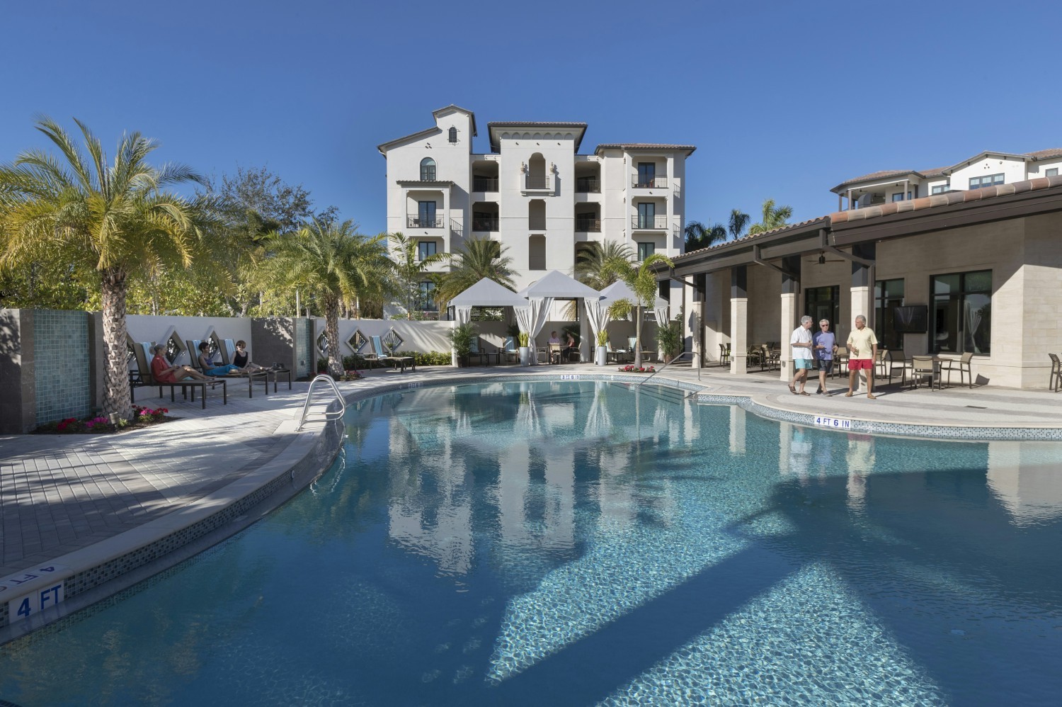 Residents relax poolside at Moorings Park at Grey Oaks.