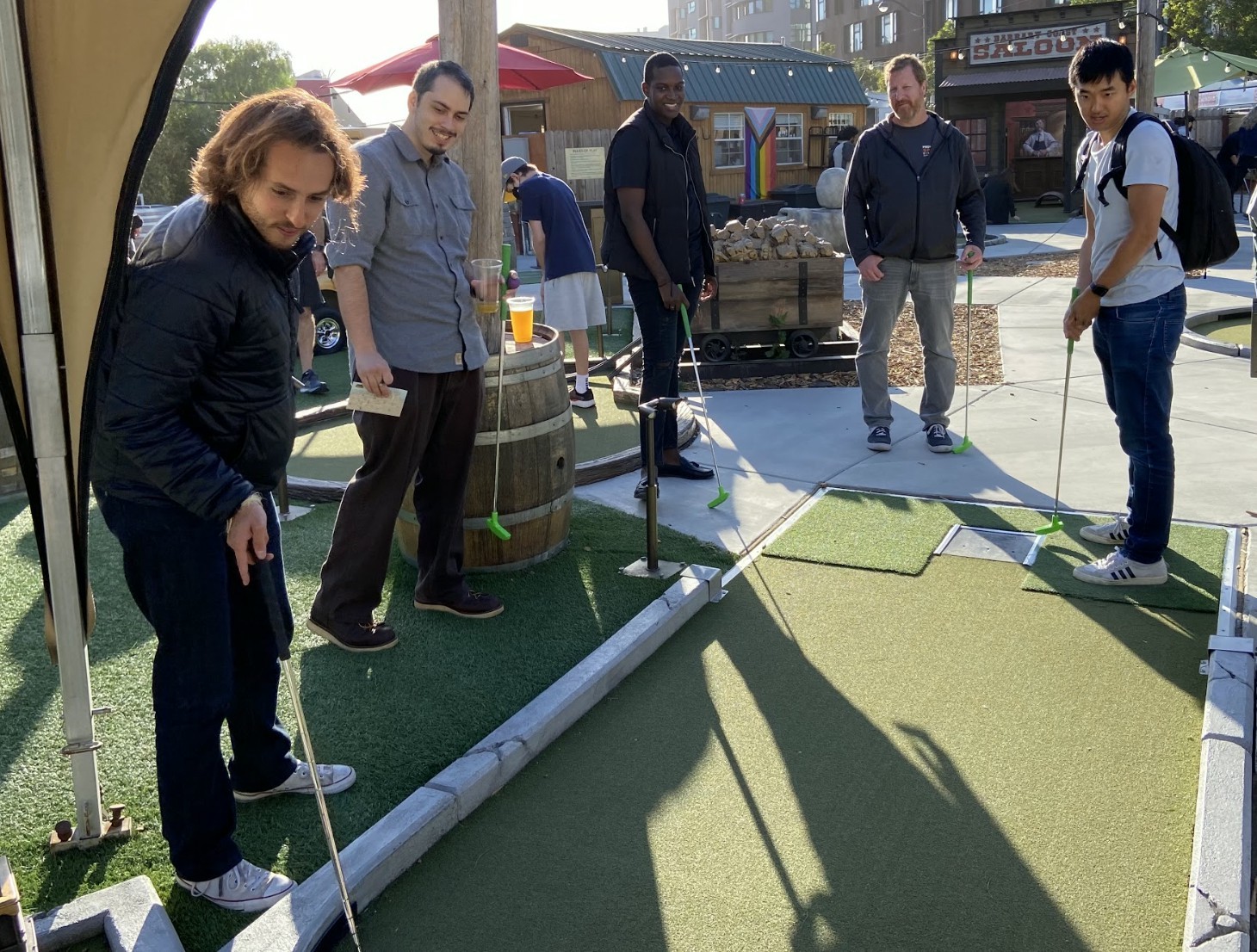 Members of our engineering and operations team play happy hour mini-golf with our CEO, Roman Pedan