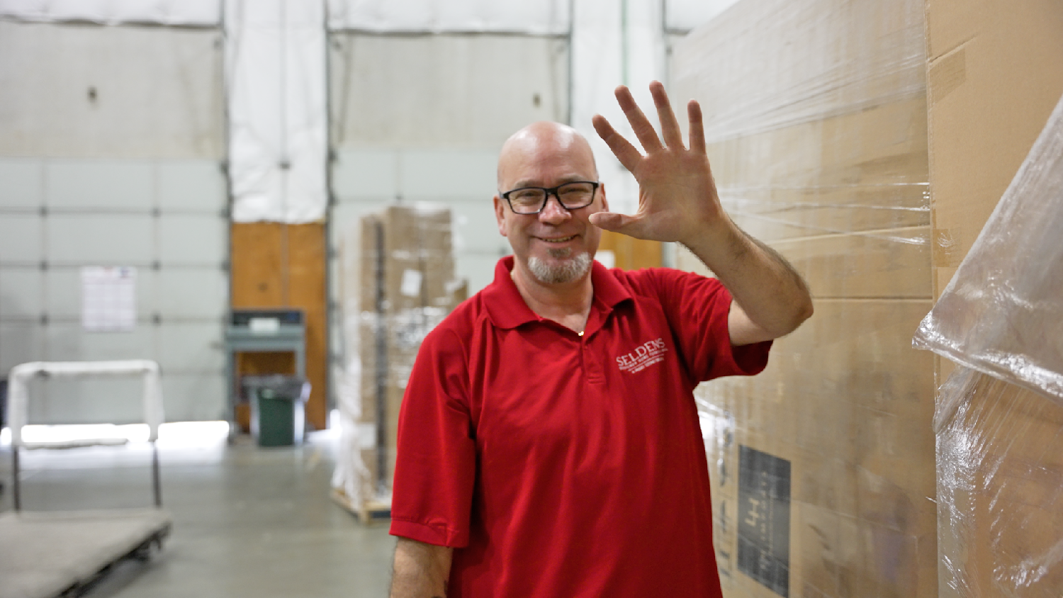 Matt waving in warehouse.