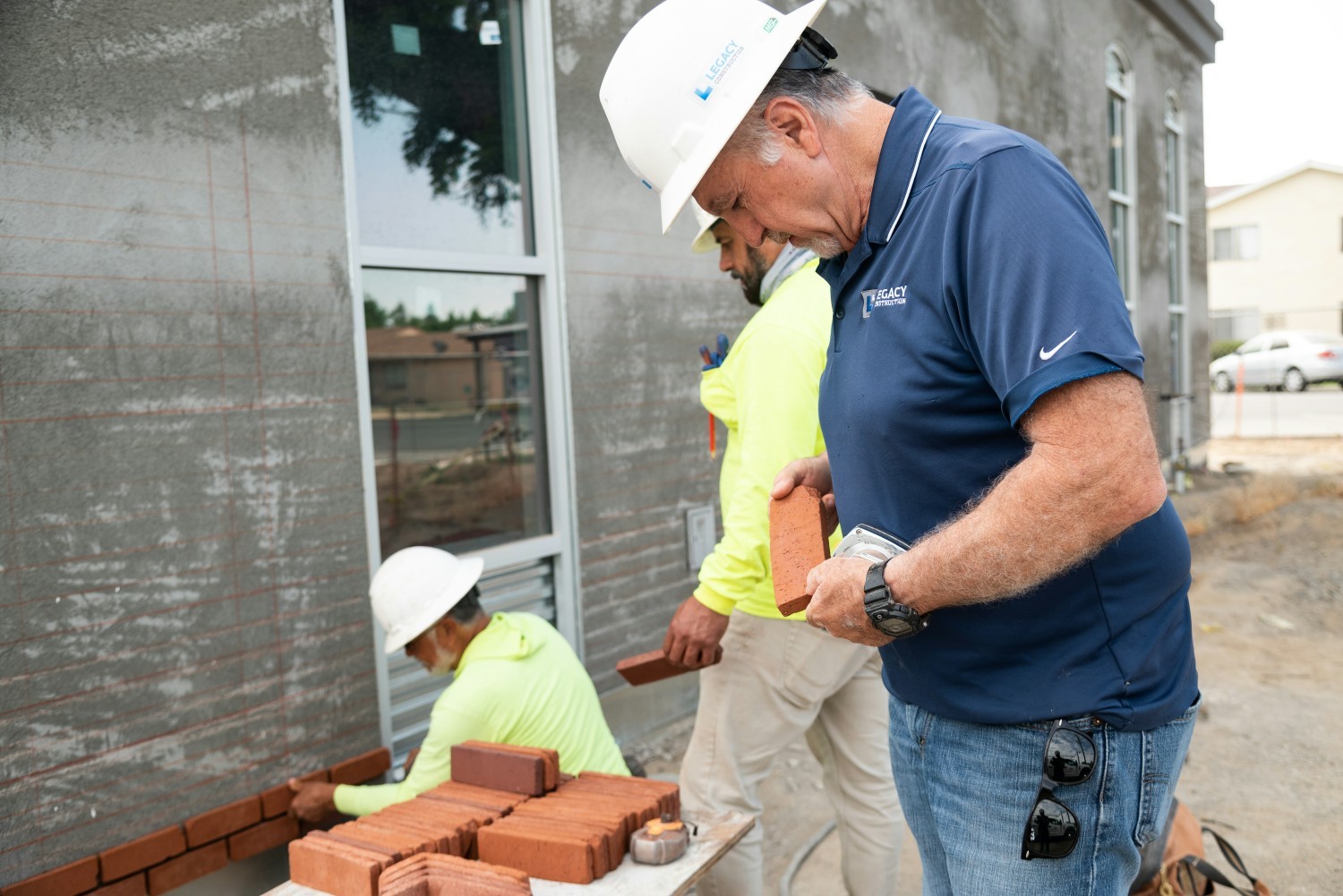 Ara checking the bricks to be laid on the exterior of a health center in progress.