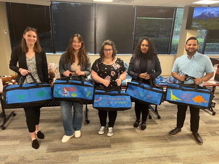 Employee volunteers decorate and fill duffle bags with essential items for children in the local foster care system